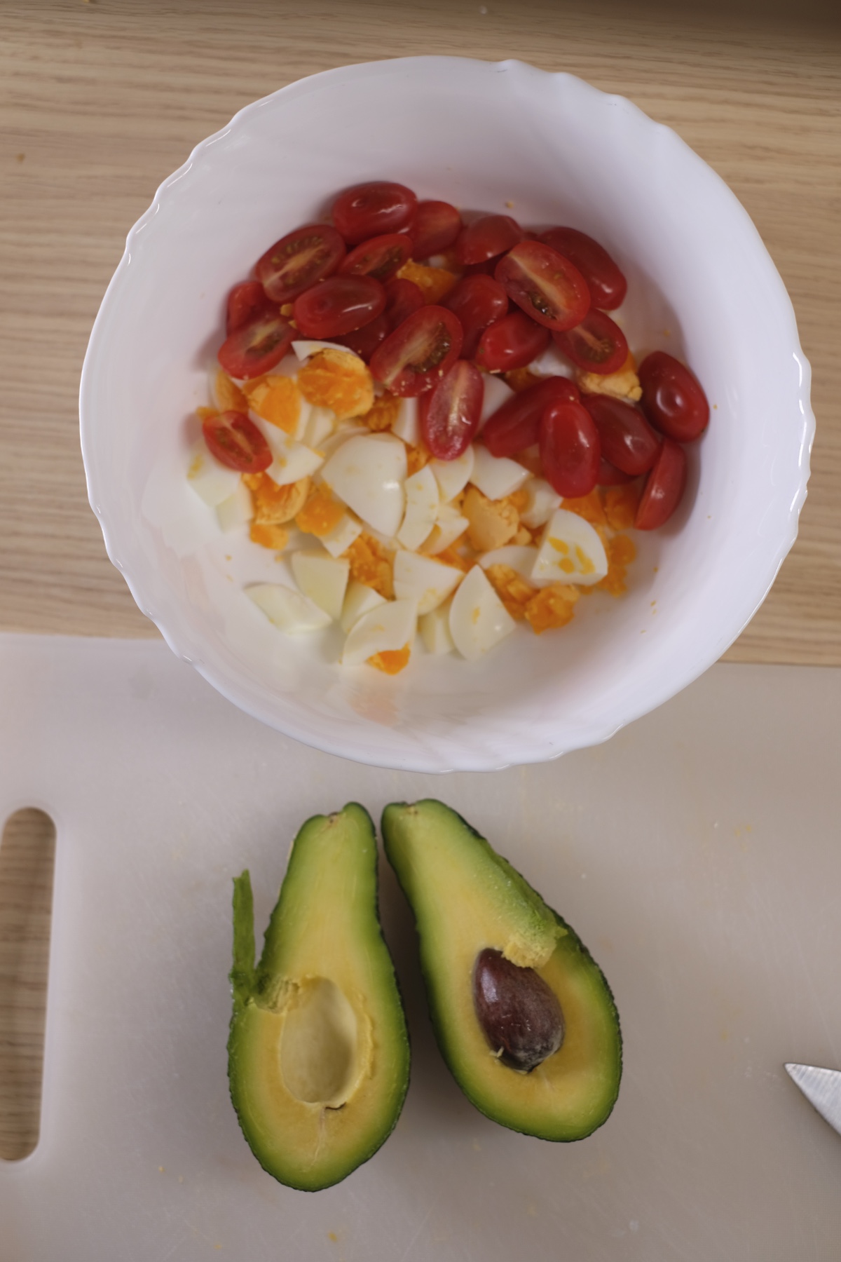 Chopped eggs and cherry tomatoes in a bowl for avocado egg salad