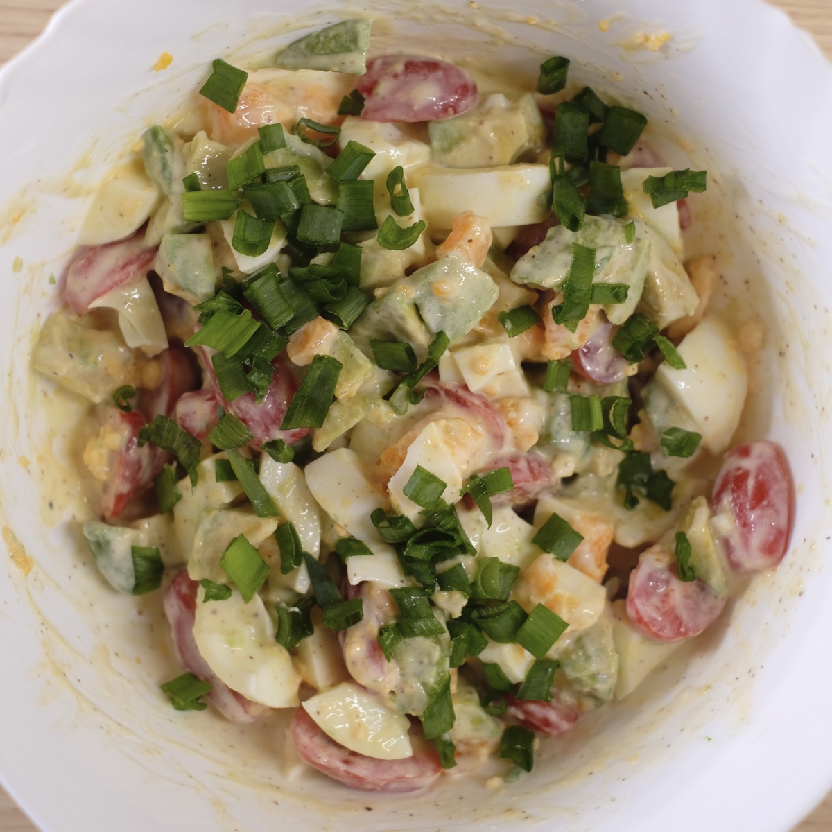 Creamy avocado egg salad with cherry tomatoes and chives ready to serve