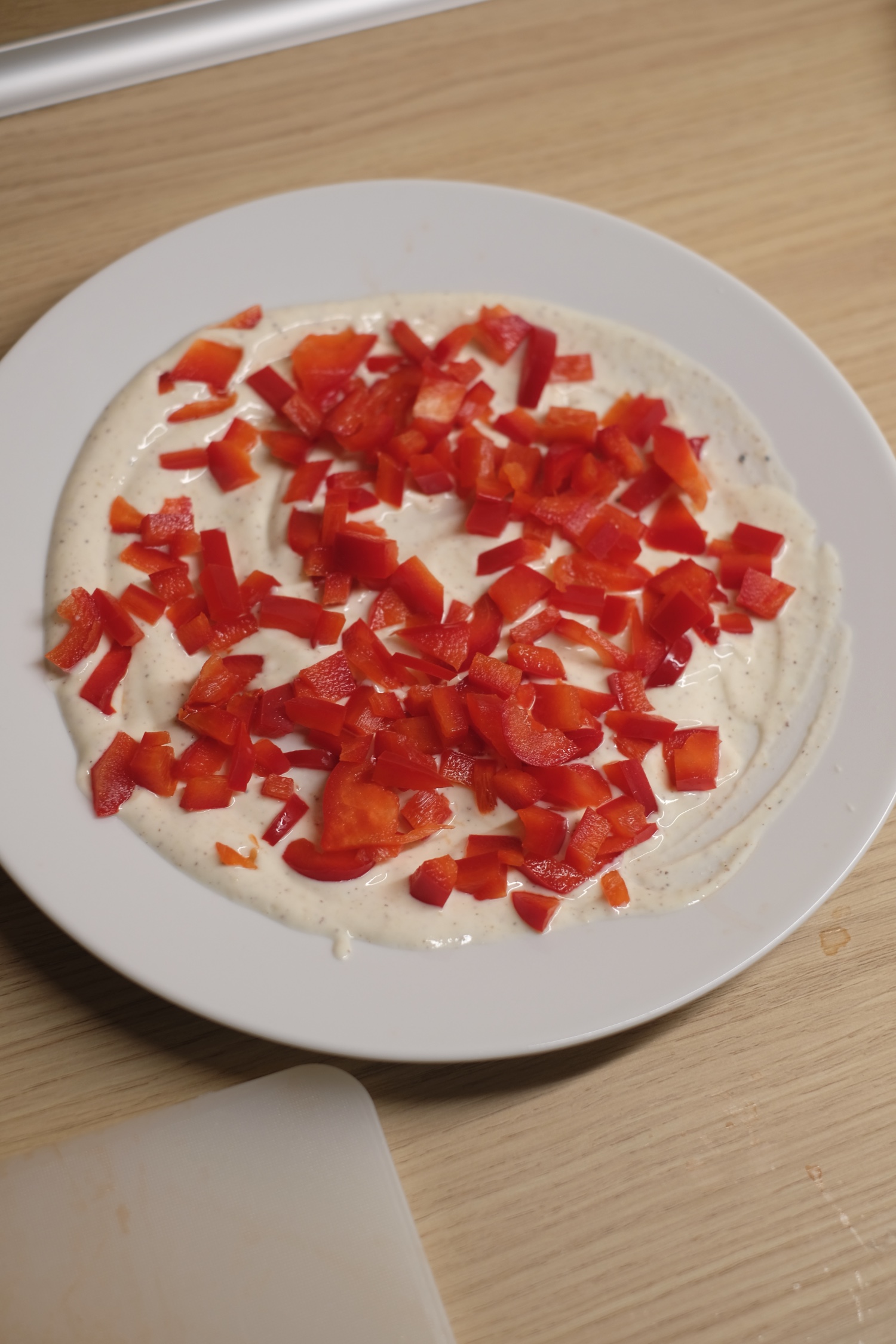 adding chopped red pepper to creamy yogurt dressing